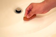 a hand is holding a toothbrush over a sink