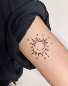 a woman's arm with a small sun and stars tattoo on the left side