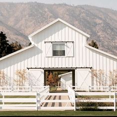 a large white barn sitting on top of a lush green field