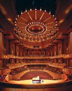 an empty auditorium filled with lots of seats and lights hanging from the ceiling above it