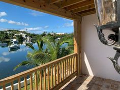 a balcony overlooking a body of water with boats in the water and palm trees on either side