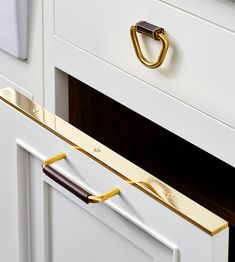 a close up of a drawer handle on a white cabinet with gold hardware and handles