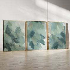 three paintings are hanging on the wall next to each other in a room with hard wood flooring