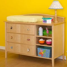 a baby crib with toys and other items on the bottom shelf in front of a yellow wall