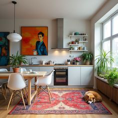 a dog laying on the floor in front of a kitchen with a table and chairs