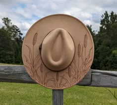 This hand burnt cattail wide brim fedora will add a charming country feel to your wardrobe. The tan material burns brown allowing the intricately burnt and shaded cattails to stand out on this nature inspired hat. The design is original and completely free-handed. For a finishing touch the hat is adorned with a warm brown faux leather hatband. This hat comes carefully packaged in a box. Each of my hats comes beautifully wrapped like a gift, and includes a note card. I would be happy to write a g Burnt Hats For Women, Felt Burning, Custom Cowgirl Hats, Burn Hats, Burning Hats, Western Hats For Women, Hats Cowgirl, Burned Hats, Diy Hats