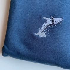 Humpback Whale breaching Embroidered Jumper.  Lovely embroidered humpback whale breaching. Soft Cotton drop shoulder style with stylish fit. Designed and Embroidered in the UK. Unisex Fit. 10% of profits goes to animal charities.  Vegan. JUMPER INFO Twin needle stitching. We use sustainable fabric and the jumper is fair trade certified. Sweatshop free and WRAP certified. Shipped in recyclable and biodegradable packaging.   SIZING UK (unisex fit) X-Small approx Size 6-8 Small approx Size 8-10 Med Humpback Whale Embroidery, Whale Embroidery Design, Whale Shark Embroidery, Men’s Embroidery, Humpback Whale Breaching, Whale Breaching, Embroidered Whale, Whale Embroidery, Jumper Design