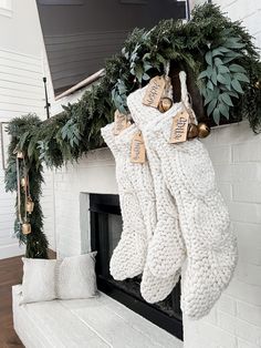 stockings hanging from the fireplace with christmas decorations around them and greenery on the mantle