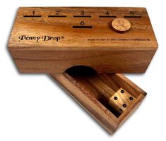 a wooden box that has some dices in it and the word penny drop written on it