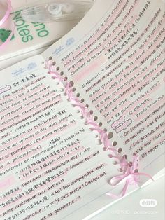 an open book with writing on it next to a pair of scissors and pink ribbon