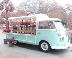 an old blue truck with flowers and bottles on the back is parked in front of a tree