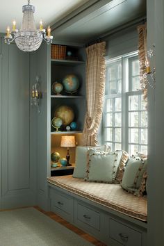 a window seat in a room next to a chandelier and bookshelf