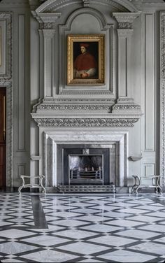 an ornate room with a fireplace and two paintings on the wall, along with marble flooring