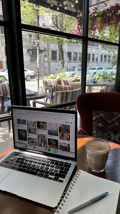 an open laptop computer sitting on top of a wooden table next to a cup of coffee