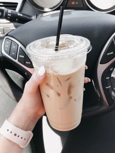 a person holding a drink in their hand while driving