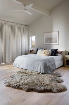 a bedroom with a bed, rug and ceiling fan in the middle of the room