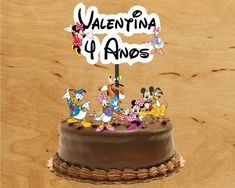 a chocolate cake topped with cartoon characters on top of a wooden table next to a wood wall