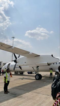 people standing around an airplane on the tarmac