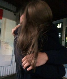 two people hugging each other in front of a building