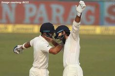 two men standing next to each other holding their hands in the air while wearing helmets