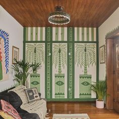 a living room with green and white wallpaper, potted plants and rugs