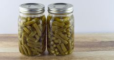 two jars filled with pickles sitting on top of a wooden table