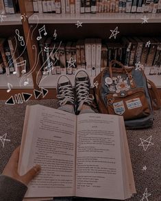 an open book sitting on the floor next to a backpack and bookshelf filled with books