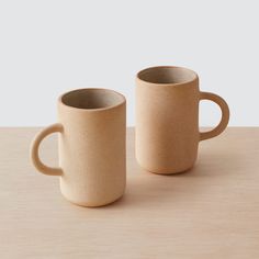 two coffee mugs sitting next to each other on a table