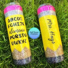 two yellow and pink glittered tumbles sitting on top of green grass next to each other