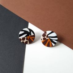 a pair of giraffe print earrings sitting on top of a white and black surface