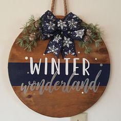 a wooden sign that says winter wonderland hanging on a wall with snowflakes and pine cones