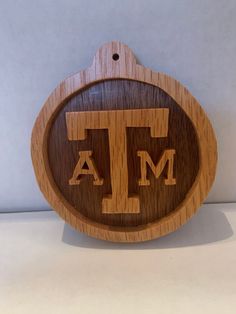 a wooden sign with the letter t on it's front and back sides, hanging from a wall