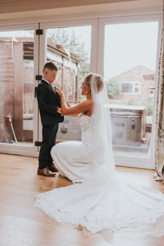 the bride and groom are getting ready for their wedding ceremony in front of an open window