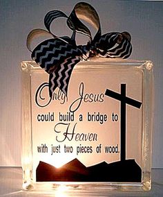 a glass block with a cross on it and a ribbon tied around the edge that says, only jesus could build a bridge to heaven with just two pieces of wood