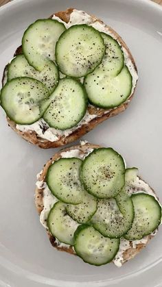 two pieces of bread with cucumbers on them are sitting on a white plate