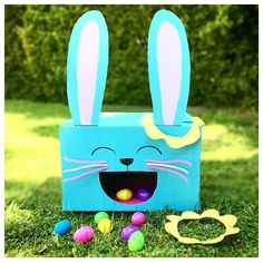 an easter bunny box in the grass with eggs around it and some decorations on the ground