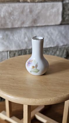 a white vase sitting on top of a wooden table