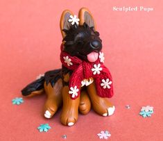 a dog figurine sitting on top of a red surface with snowflakes