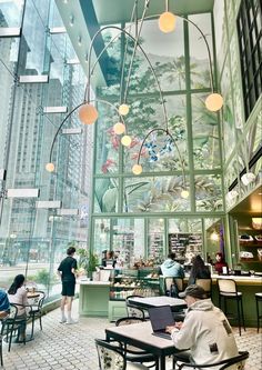 people sitting at tables in a restaurant with glass walls and ceiling murals on the wall