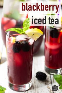 two glasses filled with blackberry lemonade and mint tea on top of a white wooden table