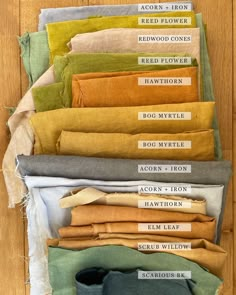 a pile of different colored linens sitting on top of a wooden floor next to each other