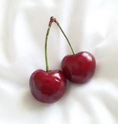 two cherries sitting on top of a white sheet