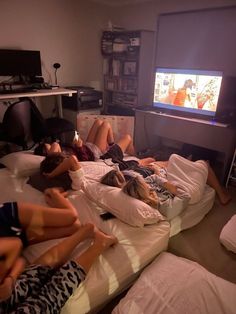 several people laying on the bed watching tv in a room with no one around them