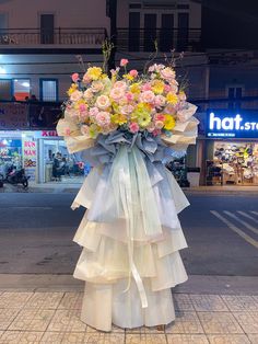 a large bouquet of flowers sitting on the side of a road in front of a store