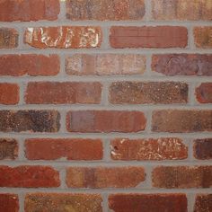 a close up of a brick wall that has been painted red and brown with yellow highlights