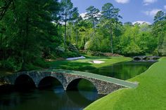 a stone bridge over a pond in the middle of a golf course