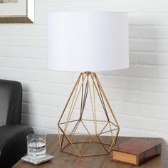 a table with a lamp on it next to a black chair and a brown book