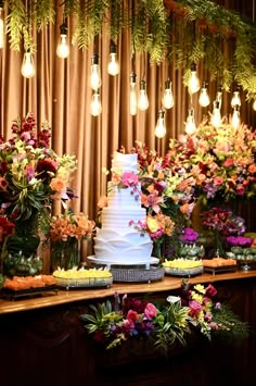 a wedding cake sitting on top of a wooden table covered in lots of colorful flowers