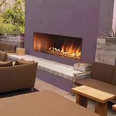 a living room with couches, tables and a fire place in front of a purple wall