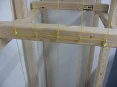 a wooden frame with yellow string attached to it